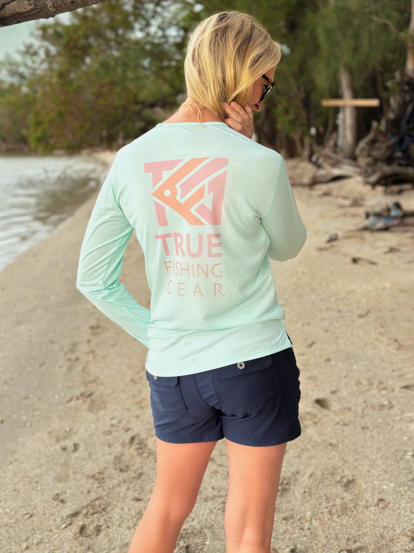 rear view of woman wearing pale mint UPF fishing shirt on beach