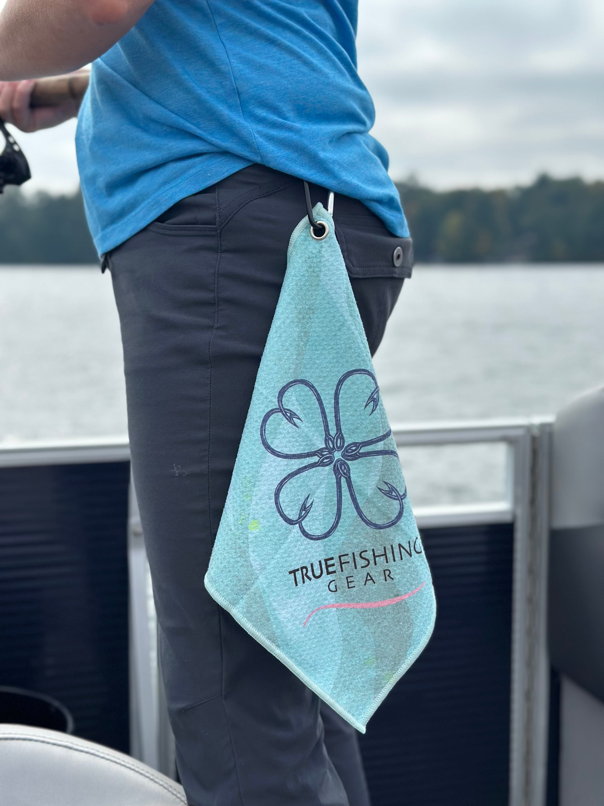 A person with a True Fishing Gear towel clipped on a belt loop on a boat
