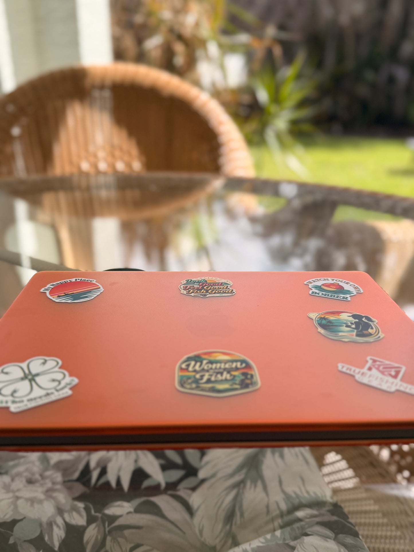 Laptop with various stickers on a glass table outdoors